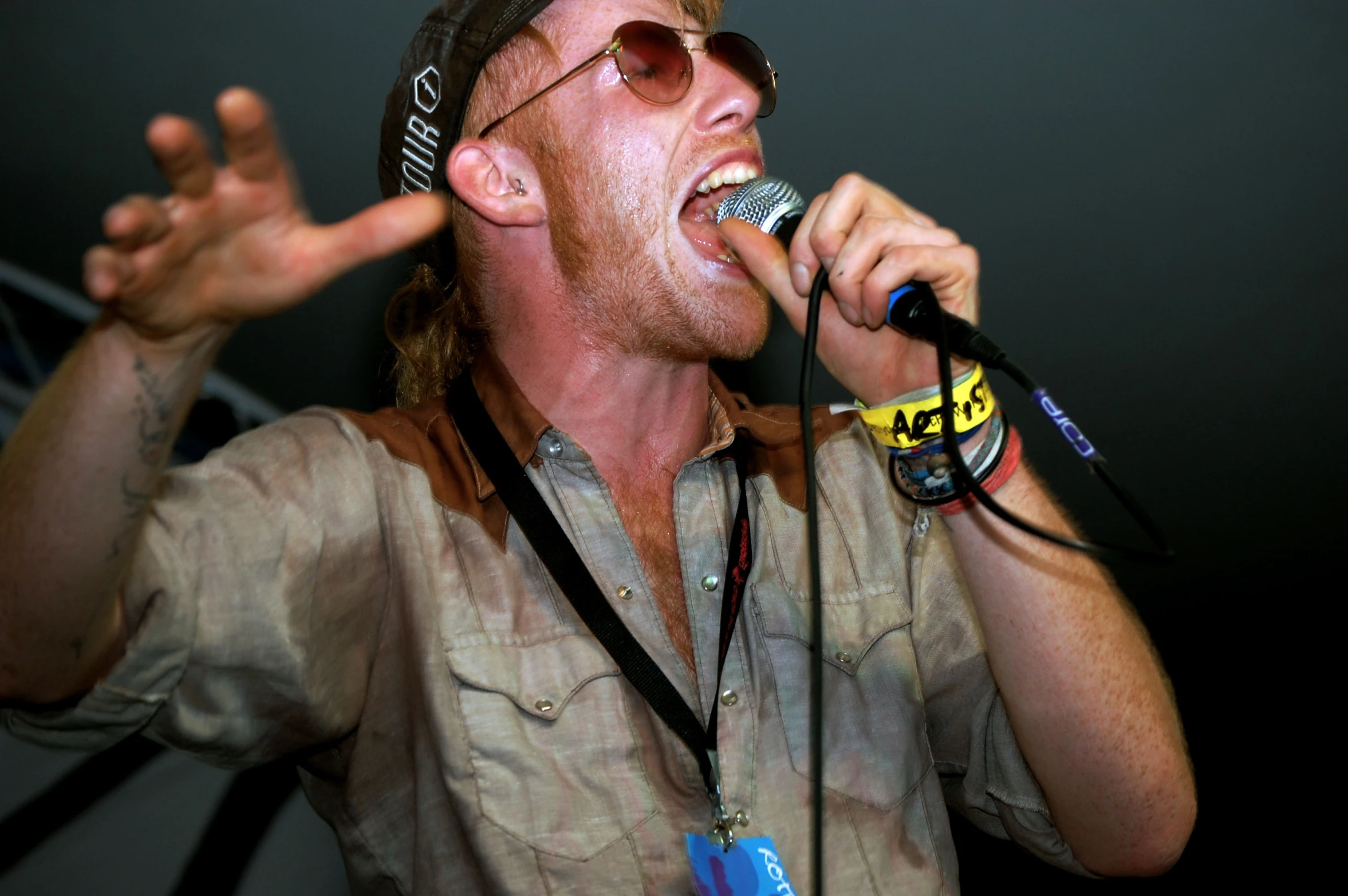 a man wearing sunglasses and singing into a microphone