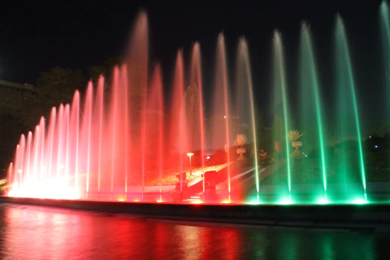 a fountain filled with lots of colorful water in the night