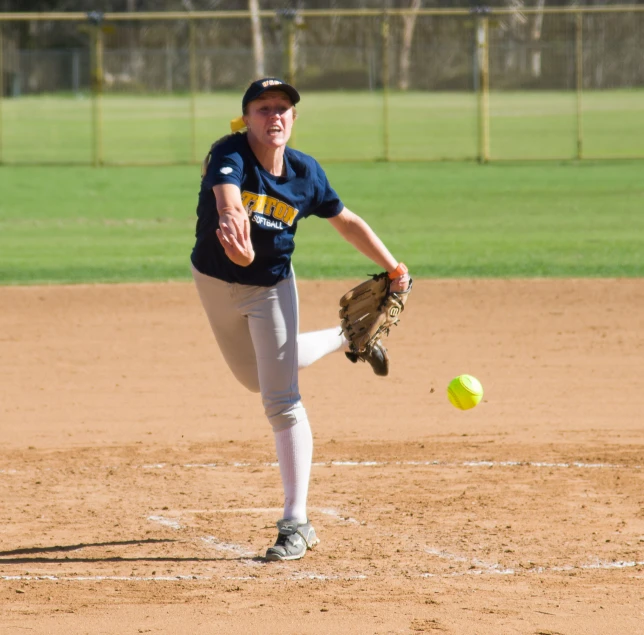 a female baseball player on the mound pitching the ball