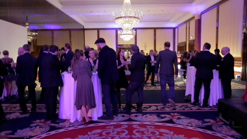 a group of people standing in a hallway next to a chandelier