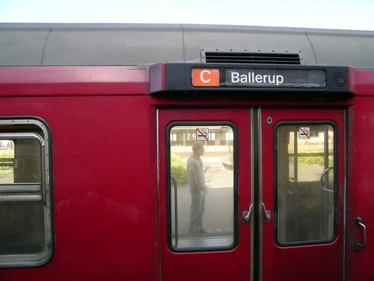 a red and black train with people walking in it