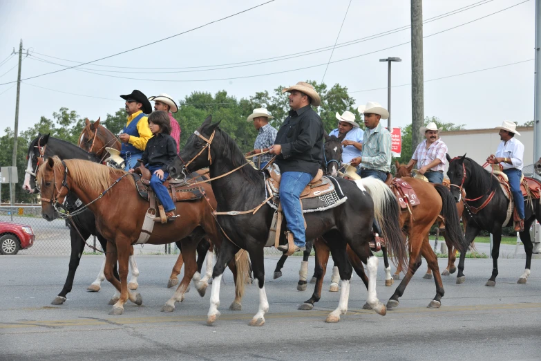 five people are riding horses in the middle of a street