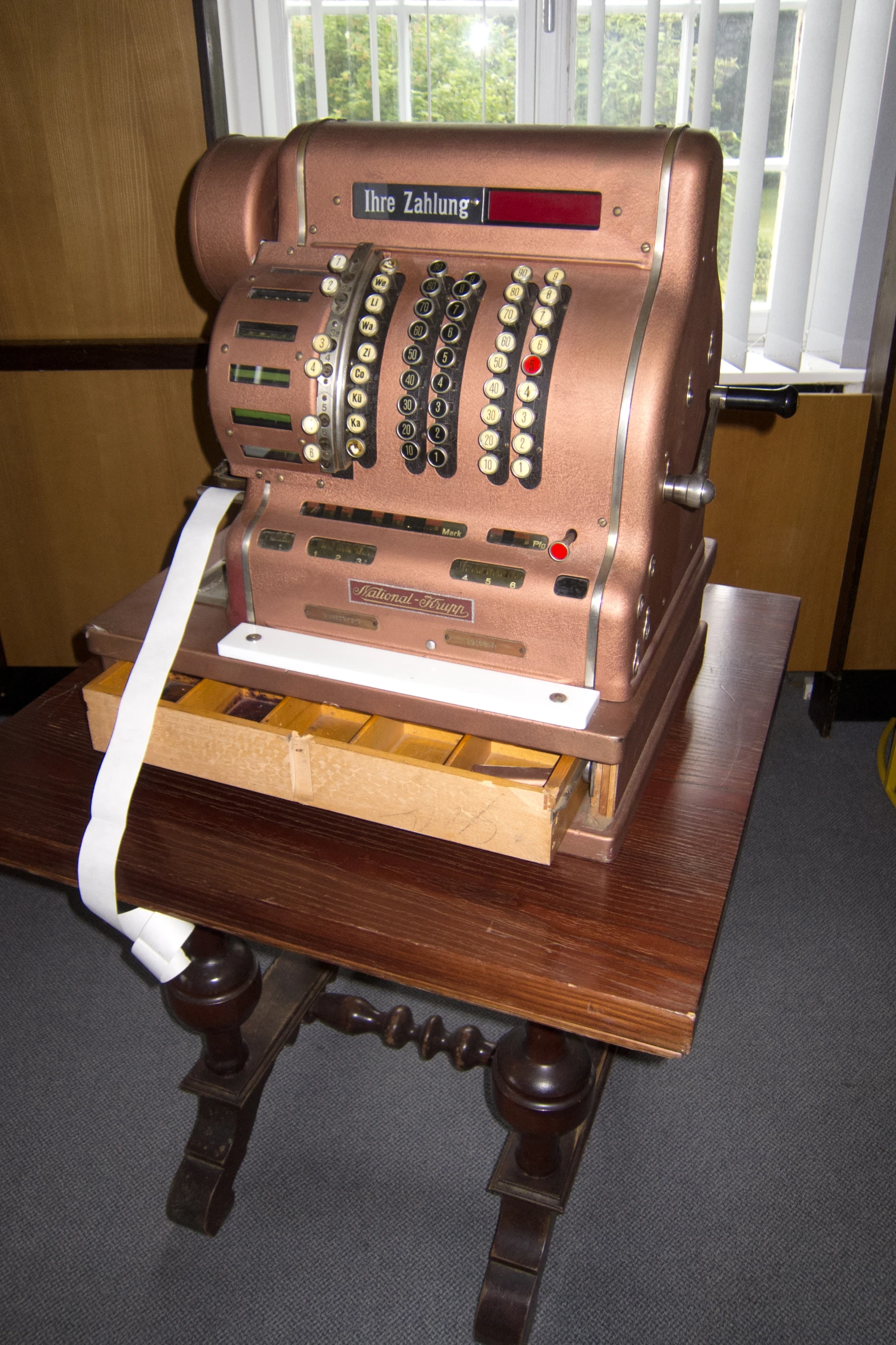 an old cash register is placed on a small table