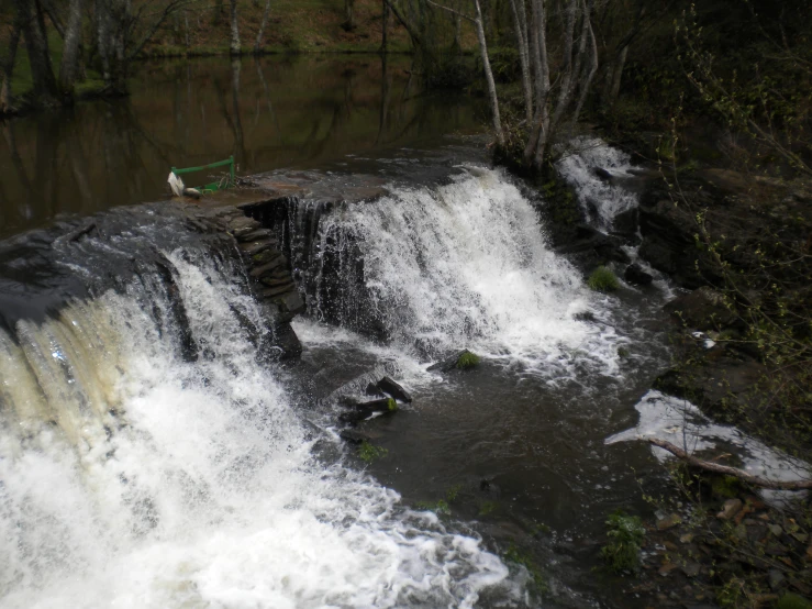 a waterfall with water flowing over it and a man standing on a rock platform