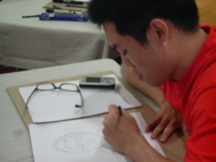 a man in an orange shirt is working on his drawings