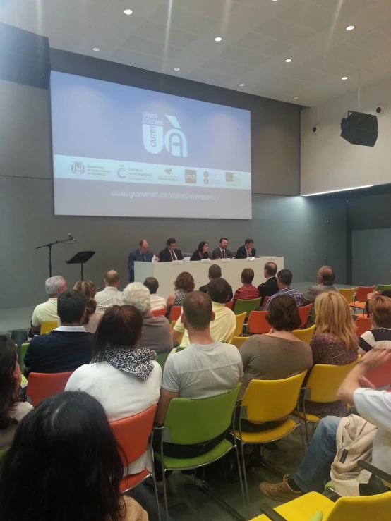 people sitting in chairs watching a presentation