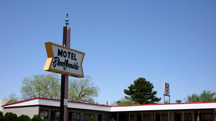 the motel is in a parking lot next to a tall sign