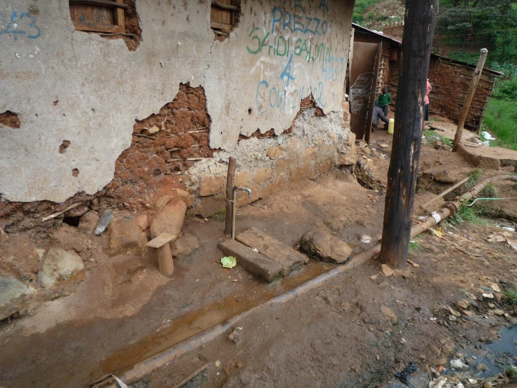 an old building with a small teddy bear sitting in the dirt next to it