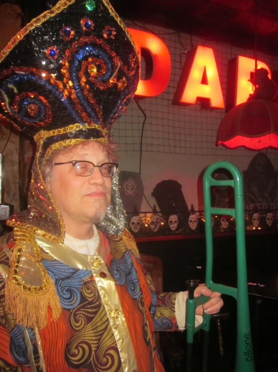 a man in costume holding a green object in front of a neon sign