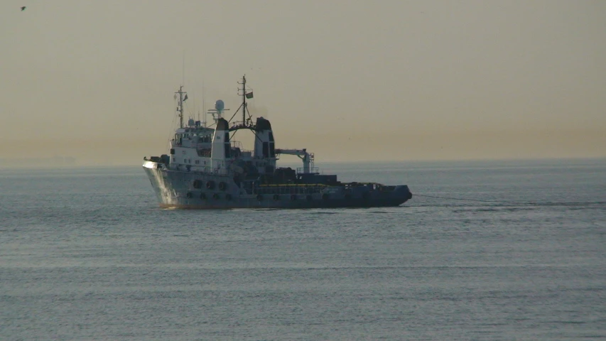 a small ship floating in the ocean with a couple of birds flying around