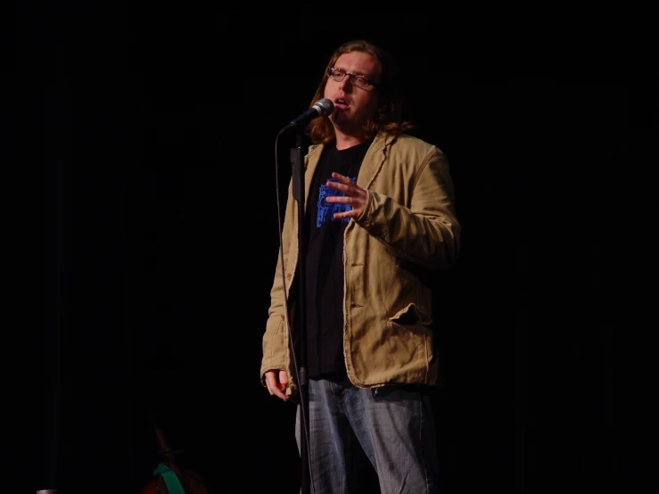 a man speaking on stage with a microphone