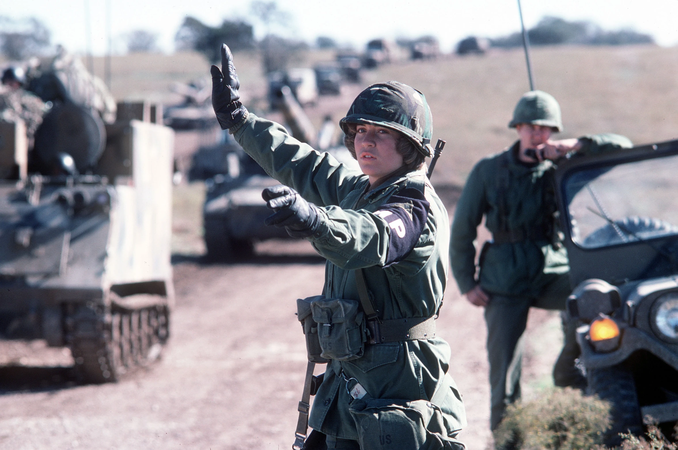 soldiers stand in front of military vehicles and talk to one another