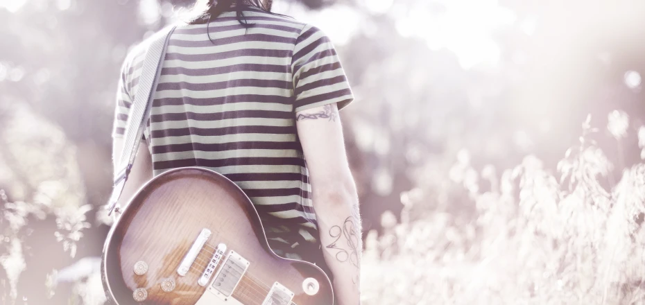 a man wearing striped shirt playing a guitar