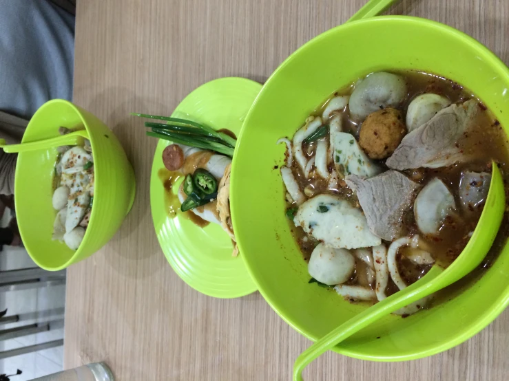 two green bowls filled with food sit on top of a wooden table