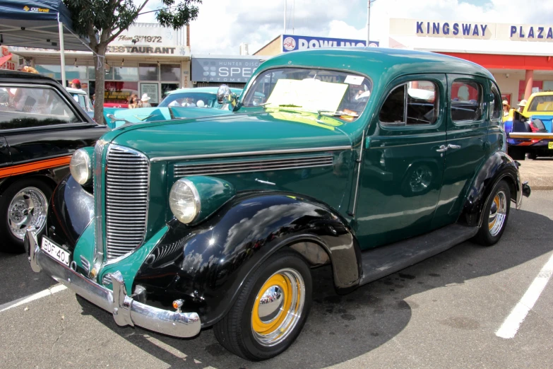 a vintage green car sitting in the street