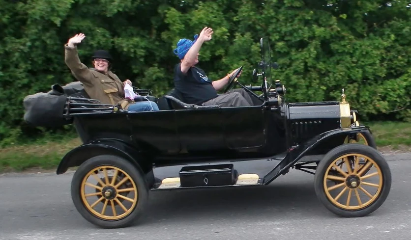 two people riding in a old style car