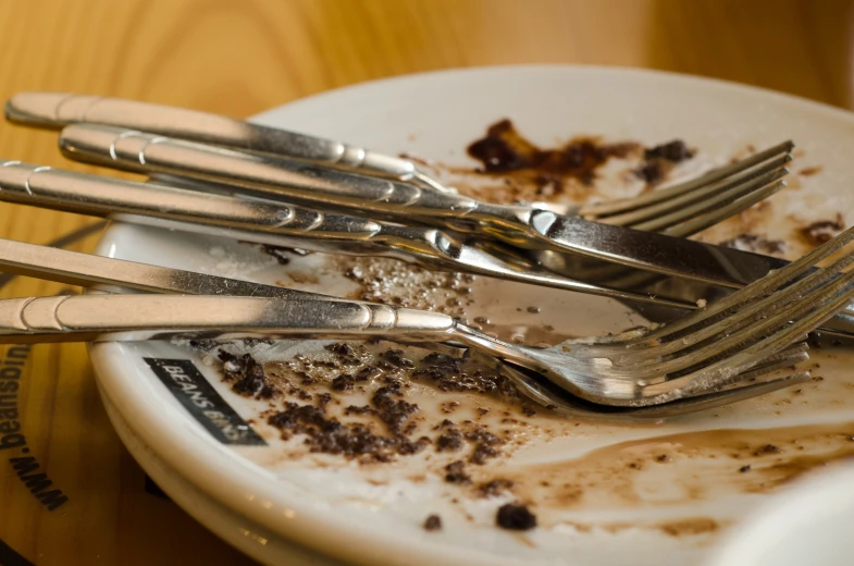 a plate with dirt on it has silver forks