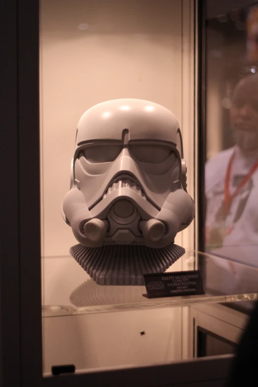the star wars helmet is on display with a man standing next to it