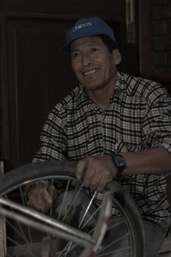 a man with a baseball cap holding onto an old bicycle wheel