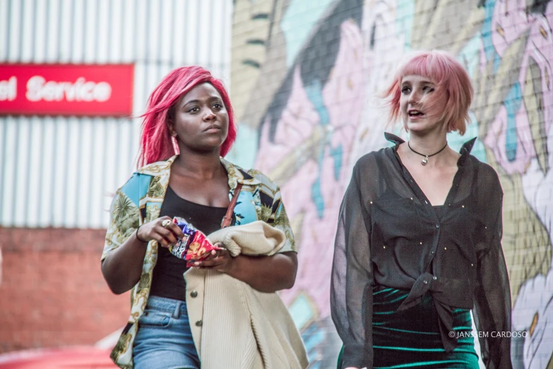 two women talking and holding colorful items outside