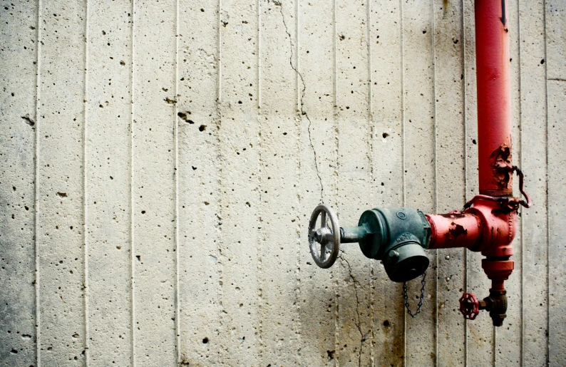 a fire hydrant attached to a wall on a concrete wall