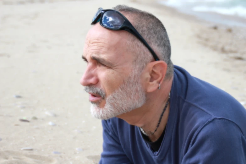 a man with sunglasses sits on the beach