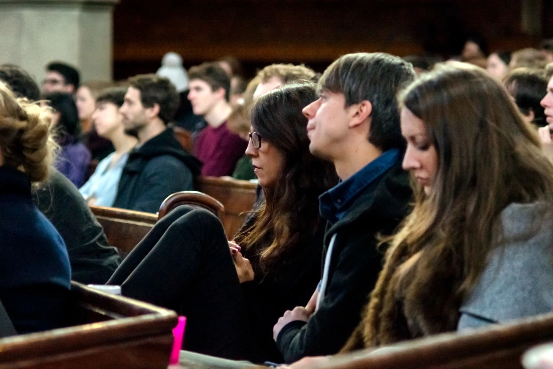 many people are sitting in small wooden chairs