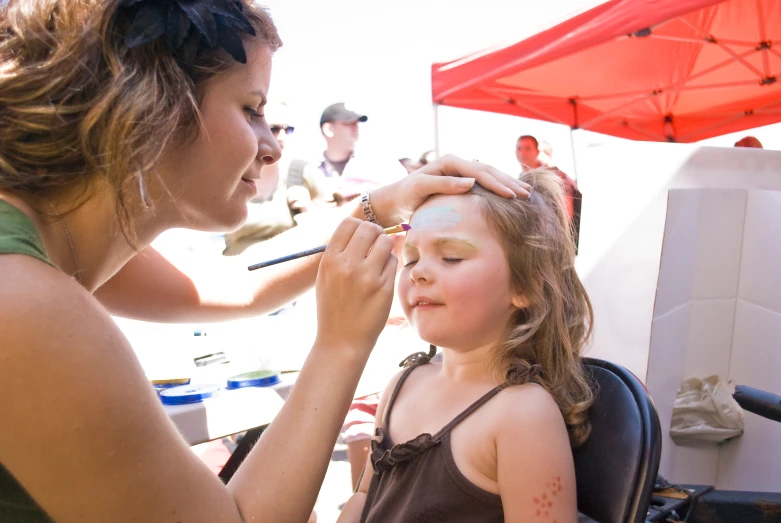 a woman working on a girl's face for a painting