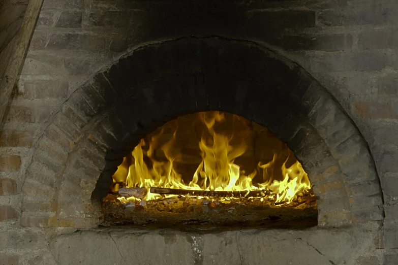 a fireplace burning in an old brick oven