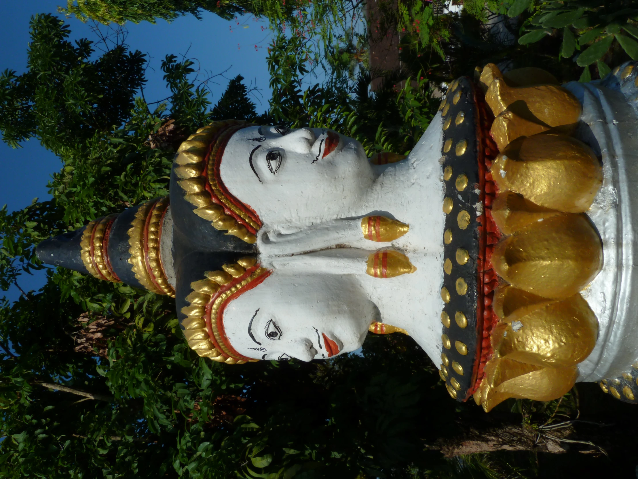 statues with gold and black decorations outside with trees in the background