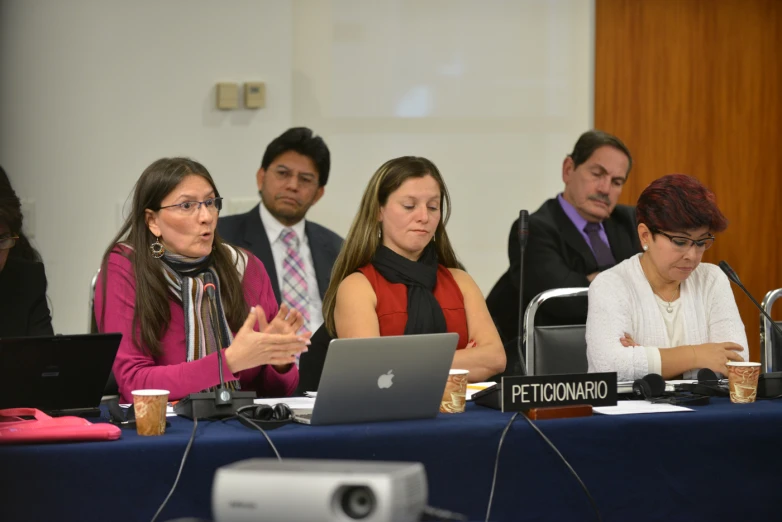 several people sitting at a table working on laptops