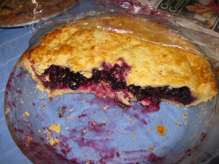 a pie cut in half on a glass plate with blueberries and other pastries