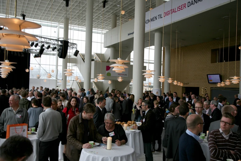 a large crowd gathers together to eat in the banquet hall