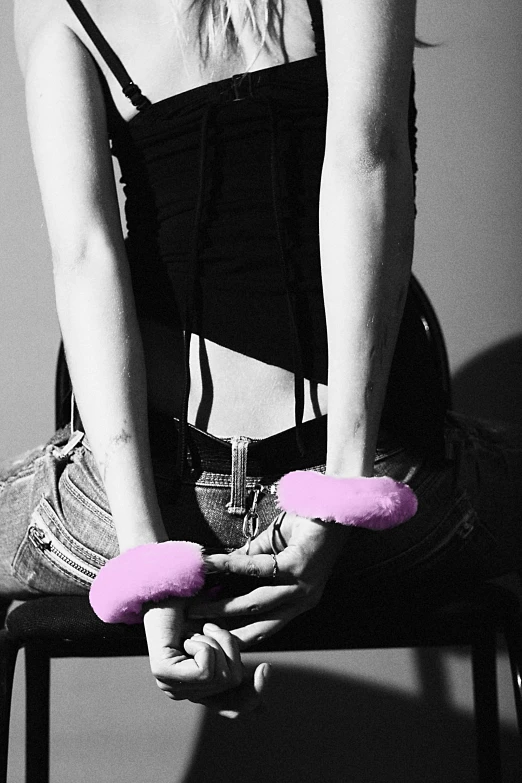 a woman sitting on a chair using the handle bars of a pink pair of scissors