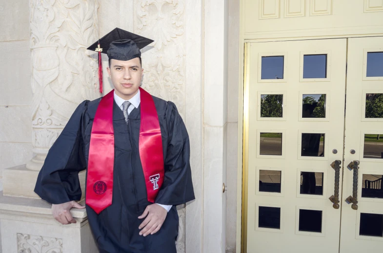 a man in graduation robes standing next to a building