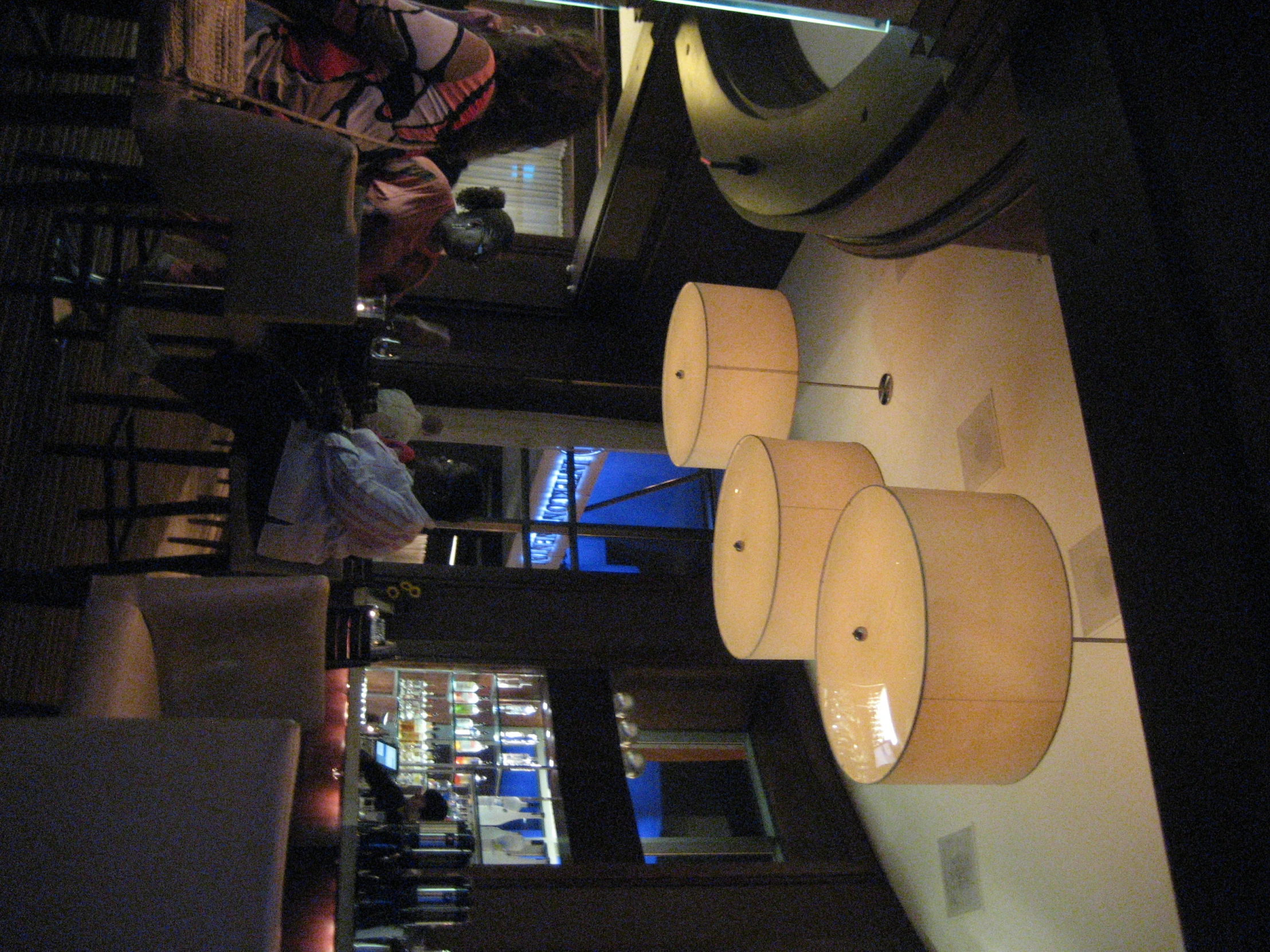 several people are sitting at a bar under lamps