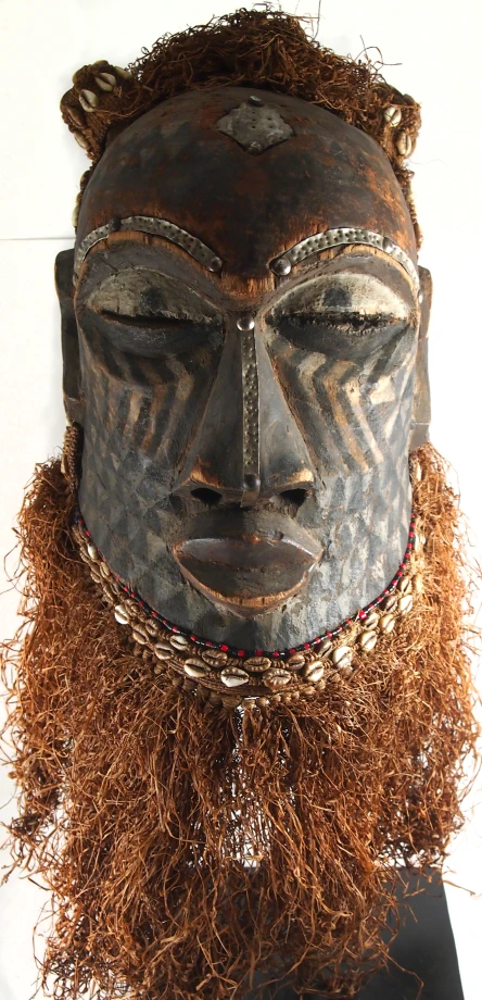 a wooden mask with long hair and a facial mask