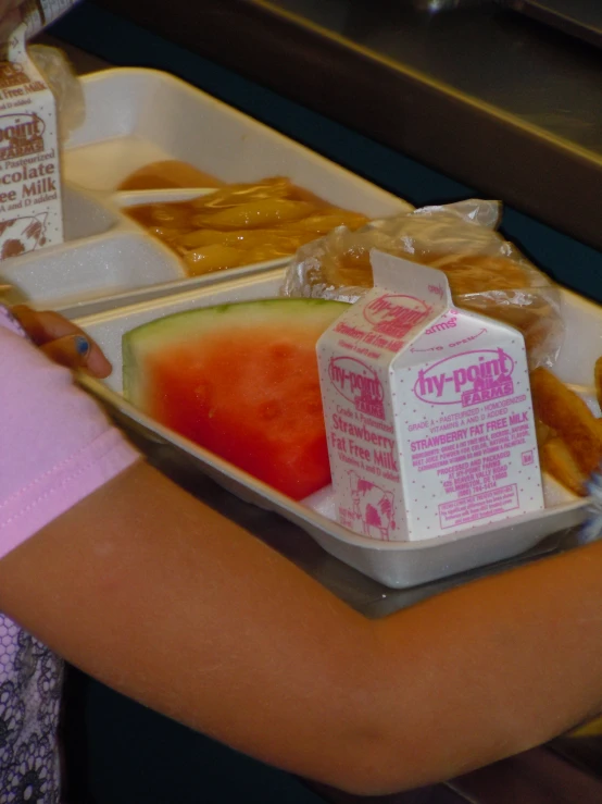 a child holds a container with some fruit