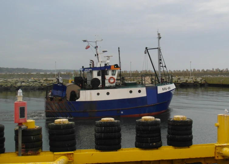 the blue and white boat is sitting near a dock