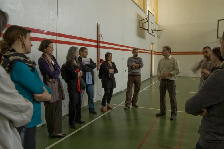 several people standing around in a large hall watching another person stand up talking