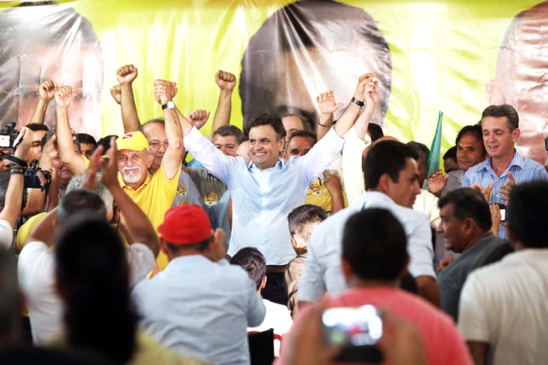 a large group of people are standing together holding up their hands