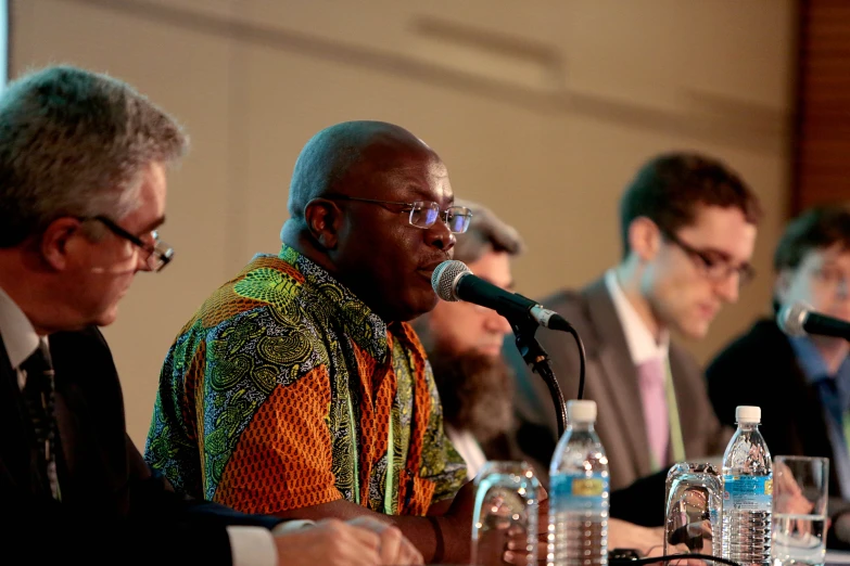 four men sitting around a table talking into microphones