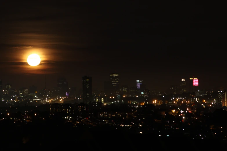 the full moon in the city skyline is pictured with lights