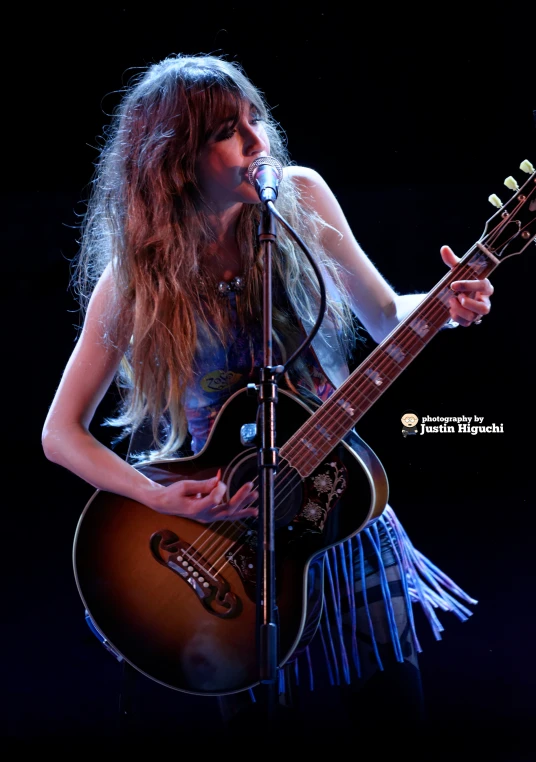 an image of woman playing a guitar on stage