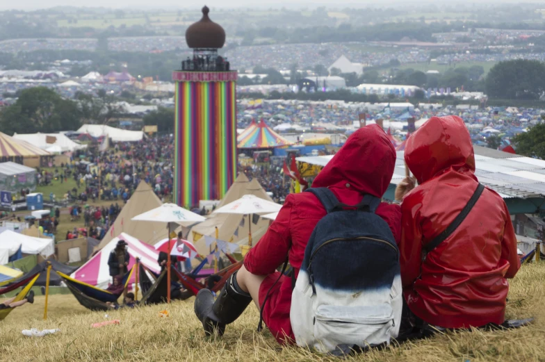 two people sitting on a hill overlooking an audience