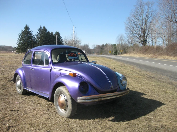 the old purple car is on the side of the road