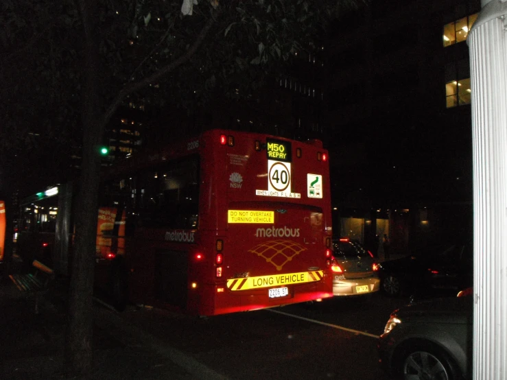 a red double - decker bus is shown at night