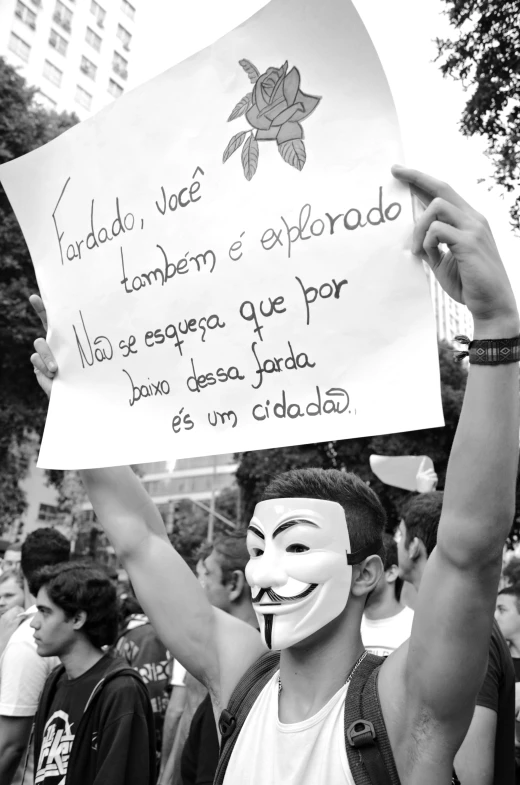 a man holding a sign and wearing a mask