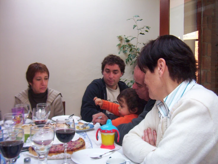 family enjoying a meal at home with the child on her lap