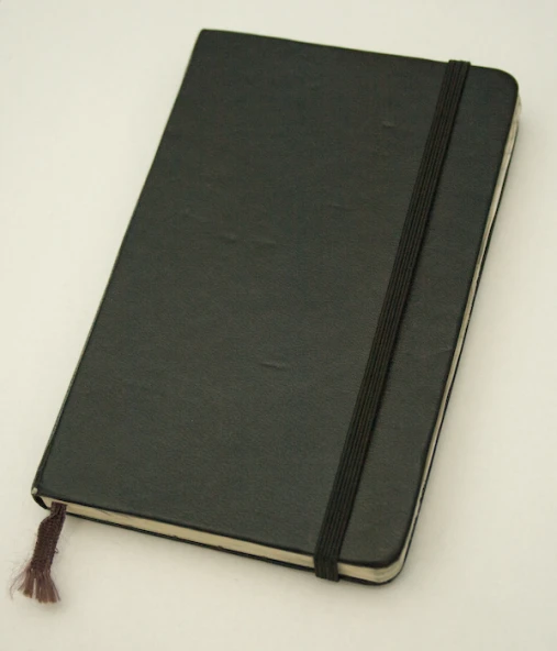 a brown book on a white surface has a tassel